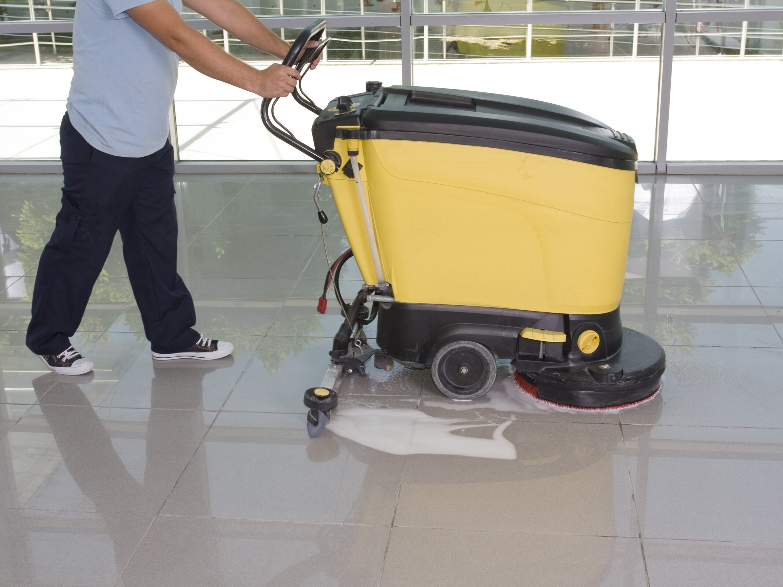 A Man worker cleaning the floor with scrubber machine. image