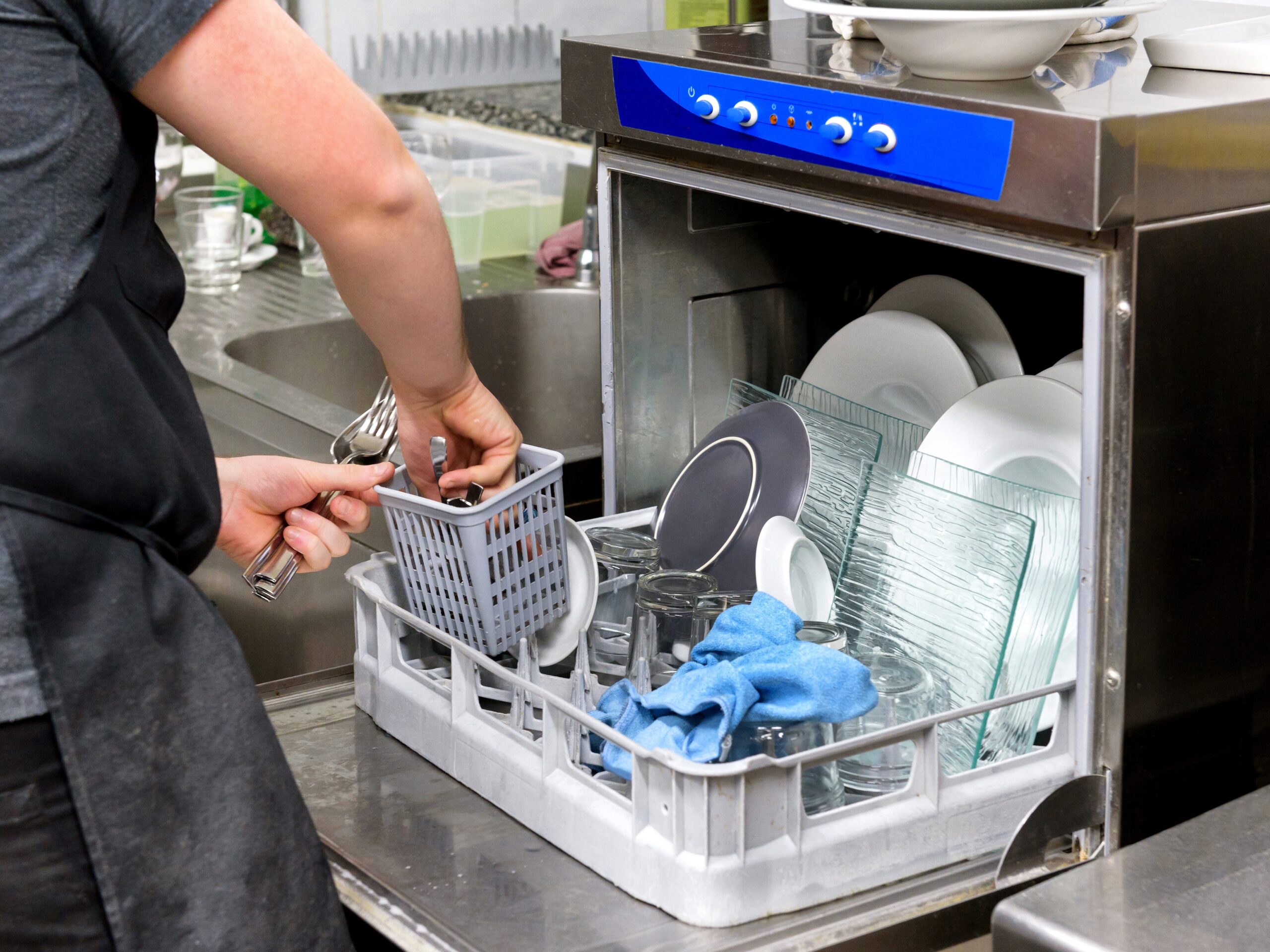 Restaurant kitchen worker emptying a dishwasher